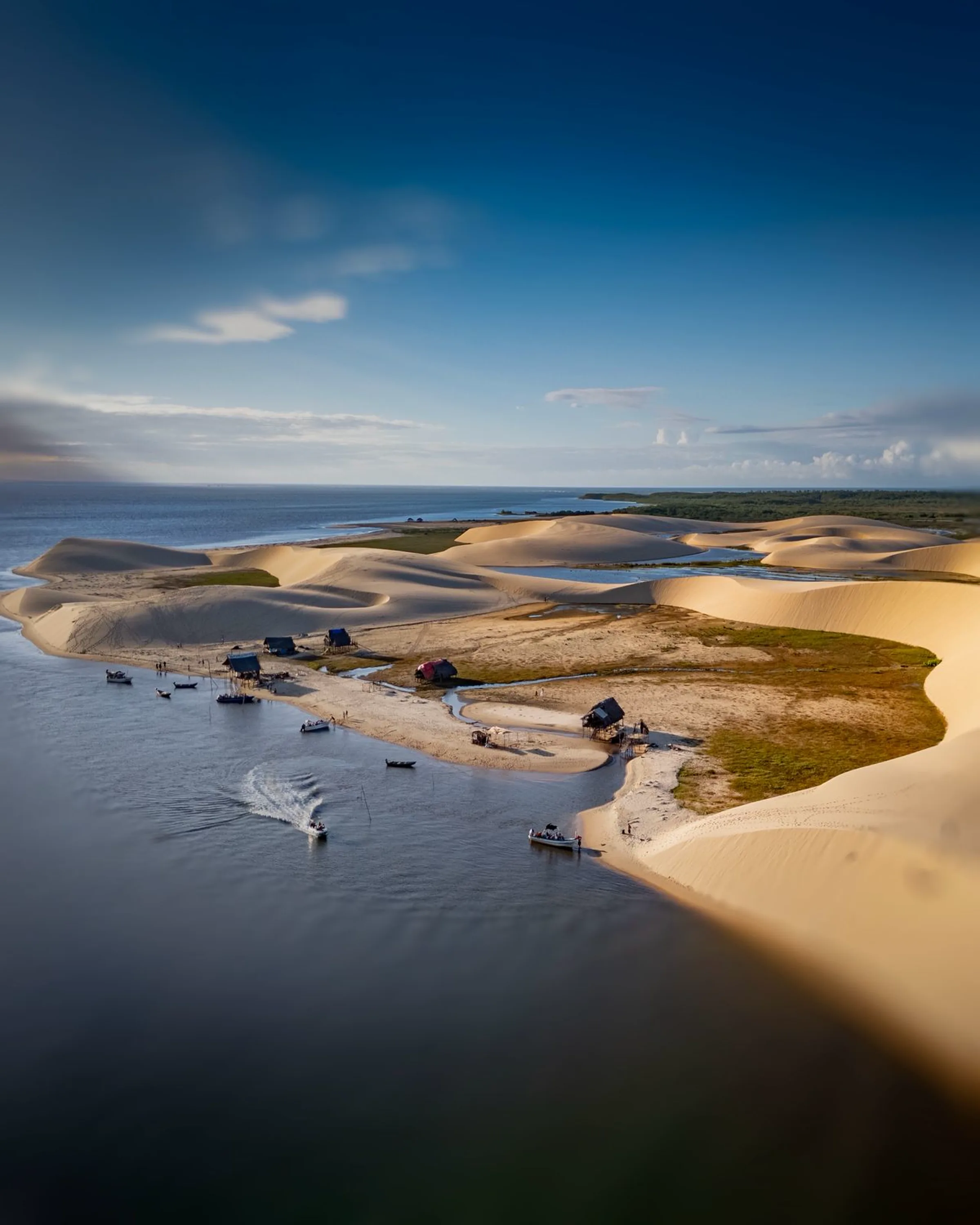 Vista aérea do Delta do Parnaíba com dunas brancas, casas de palafita e embarcações na foz dos rios